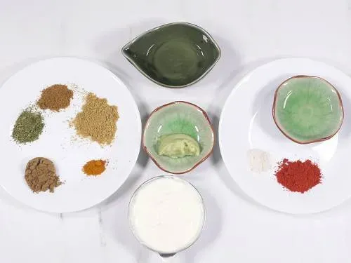 Zutaten für die Hähnchenmarinade, darunter Joghurt, Gewürze und Hähnchenstücke.