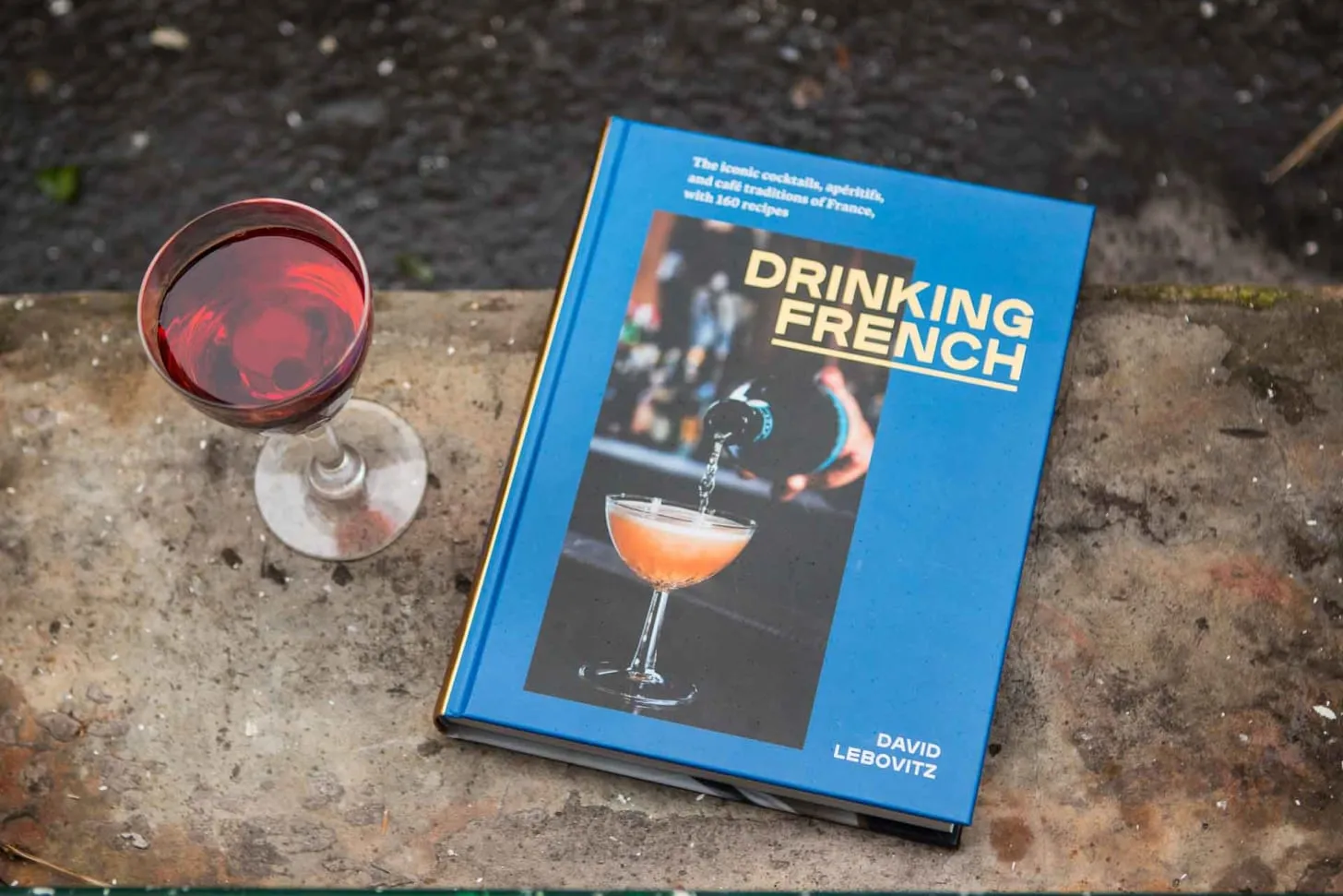 Zutaten für einen Kir: Eine Flasche Crème de Cassis und eine Flasche Weißwein auf einem Holztisch