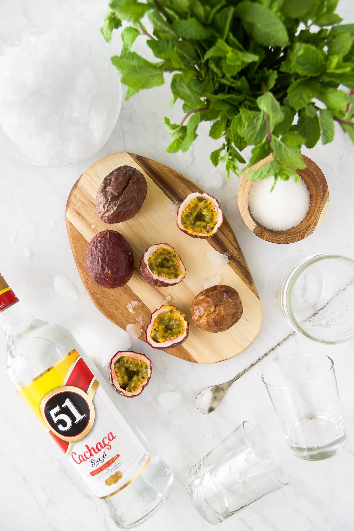 Zutaten für Passionsfrucht Caipirinha auf Marmorplatte: Passionsfrüchte, Cachaça und Zucker