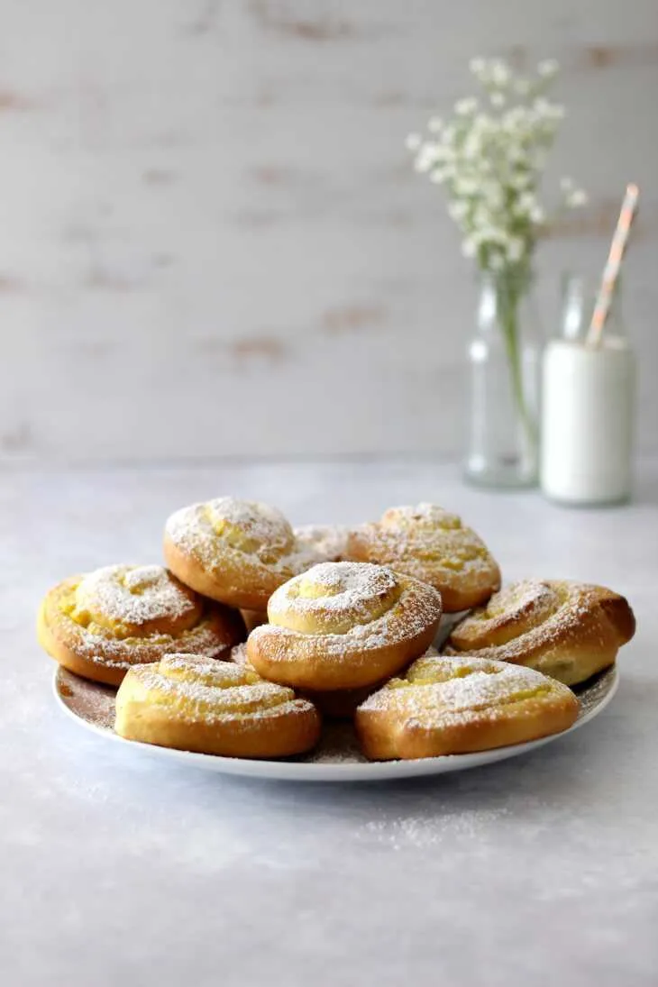 Zwei Backbleche voller frisch geformter Puddingschnecken vor dem Backen