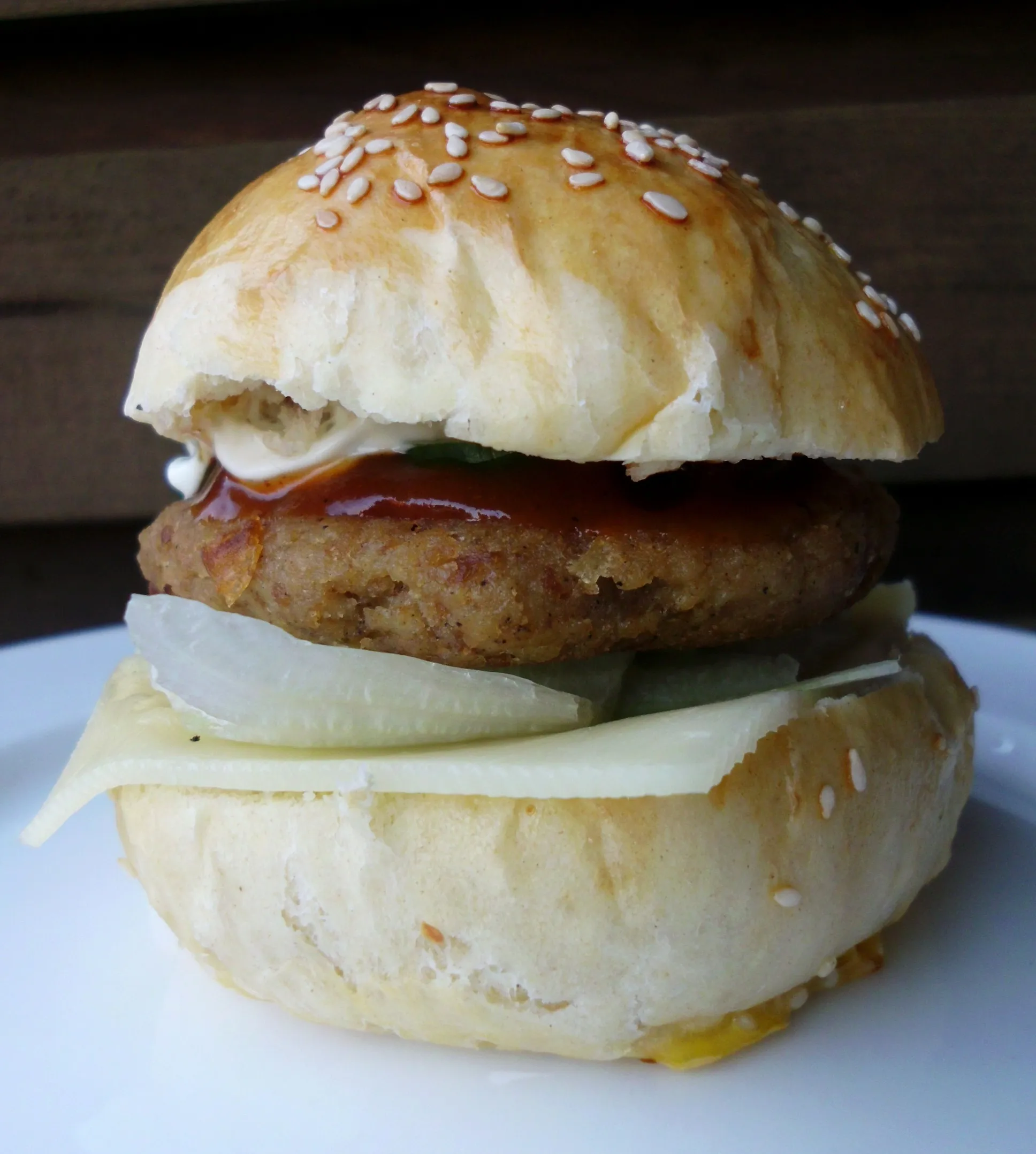 Zwei perfekt gebackene goldbraune Hamburger Brötchen mit Sesam auf einem Holzbrett