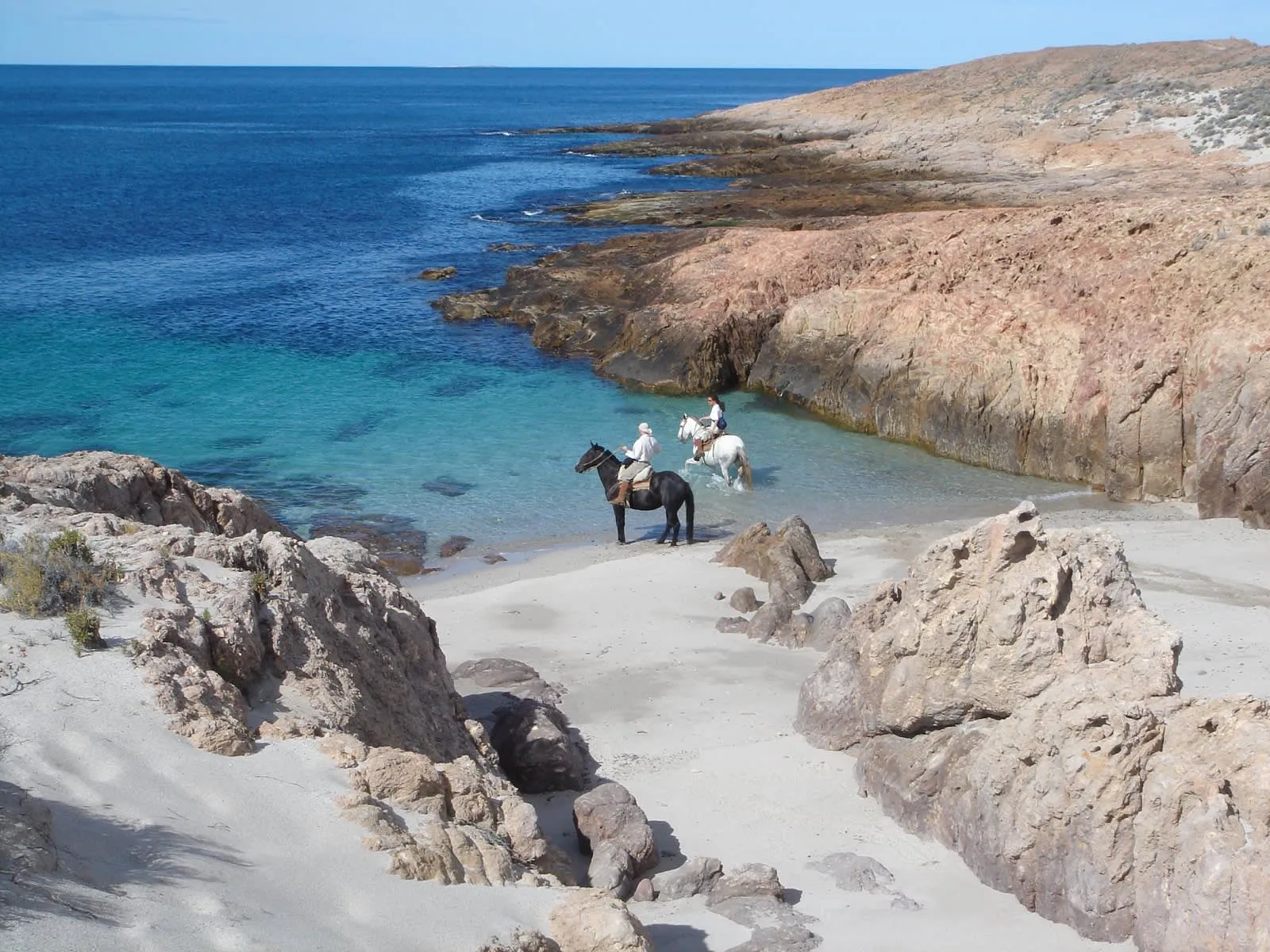 Zwei Reiter am Strand der unberührten Bahia Bustamante Bucht in Argentinien