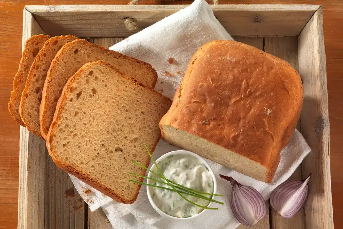 Zwei Scheiben Brot aus dem Brotbackautomaten mit einer Schüssel Quark und Schnittlauch