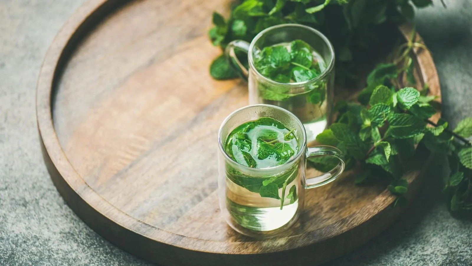 Zwei Tassen frischer Pfefferminztee auf einem rustikalen Holztablett