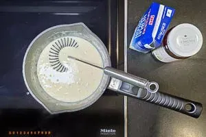 Brühe und Milch unter schnellem Rühren dazugeben und aufkochen lassen