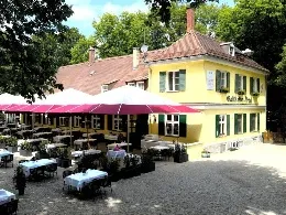 Das Teatro Solln im Iberl von außen, mit Sitzgelegenheiten im Freien und einem gelben Gebäude.