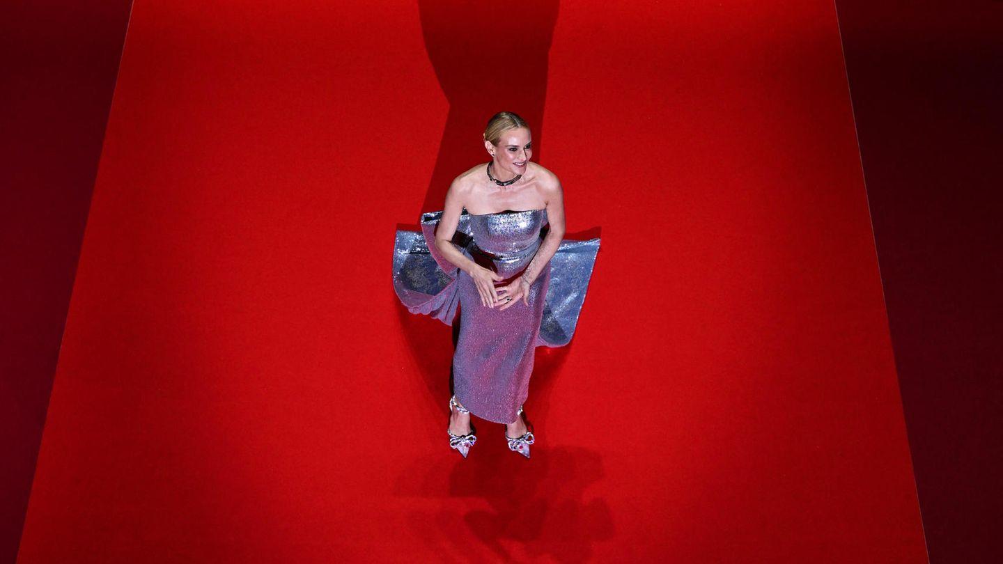 Diane Kruger in einem eleganten roten Kleid auf dem roten Teppich, strahlend und selbstbewusst