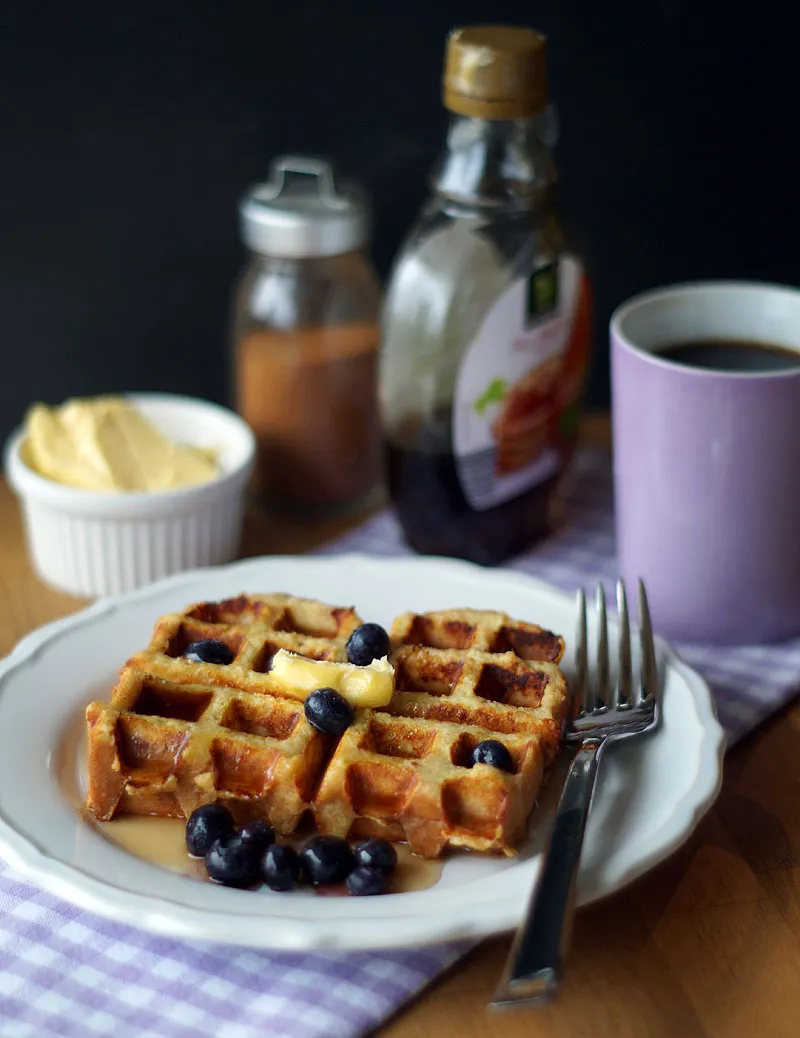 Drei Waffeln auf einem Teller, eine davon wird gerade aus dem Waffeleisen genommen
