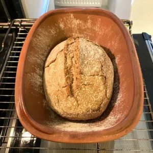 Ein fertig gebackenes Sauerteigbrot ruht auf einem Gitter