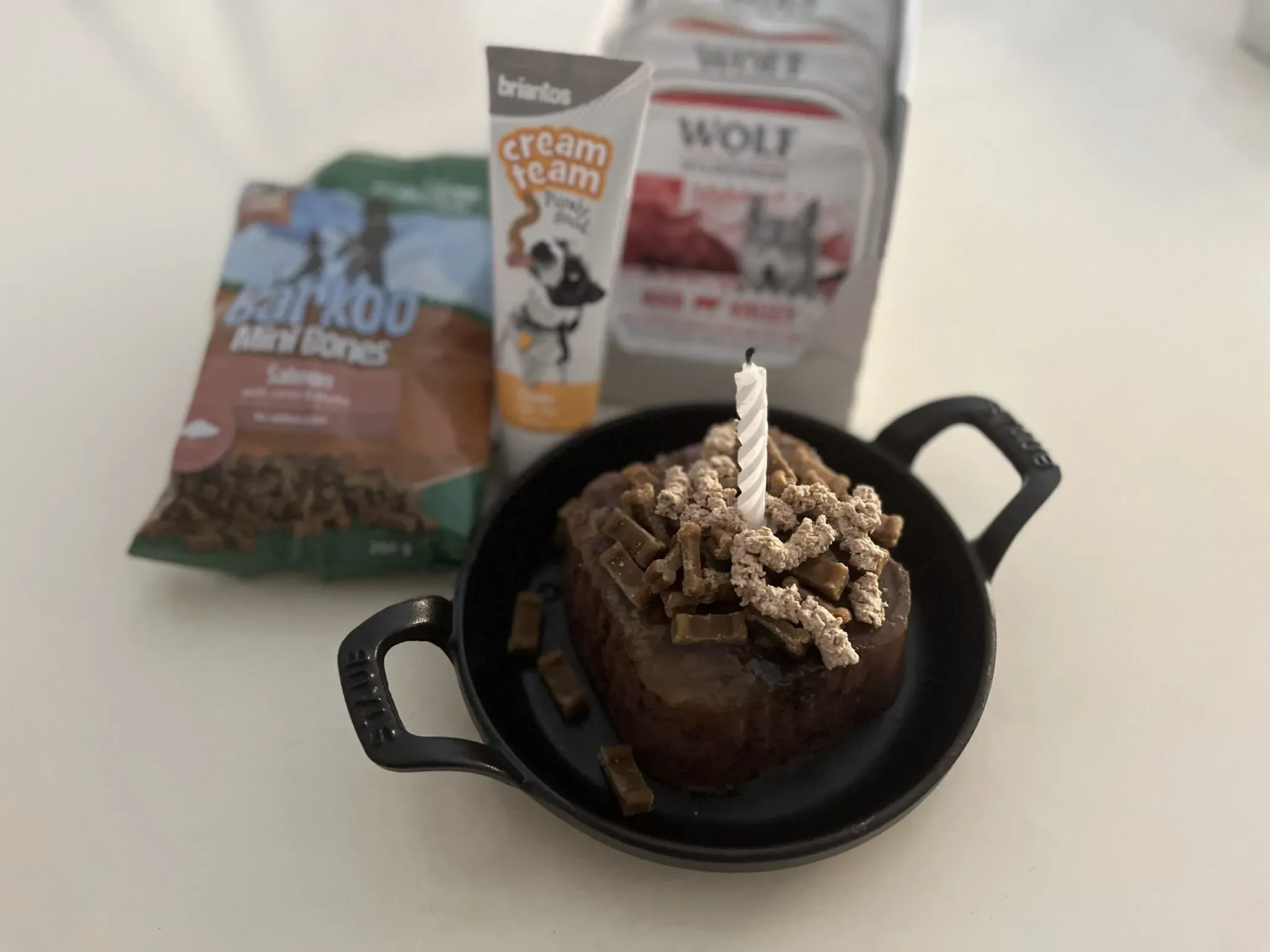 Ein Hundekuchen aus Nassfutter, garniert mit Hundepaste und Leckerlis, steht auf einem Teller.