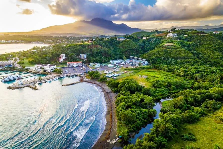 Ein luftiger Blick auf Puerto Plata in der Dominikanischen Republik mit einem Strand, grünen Hügeln und vereinzelten Gebäuden im sanften Sonnenlicht.