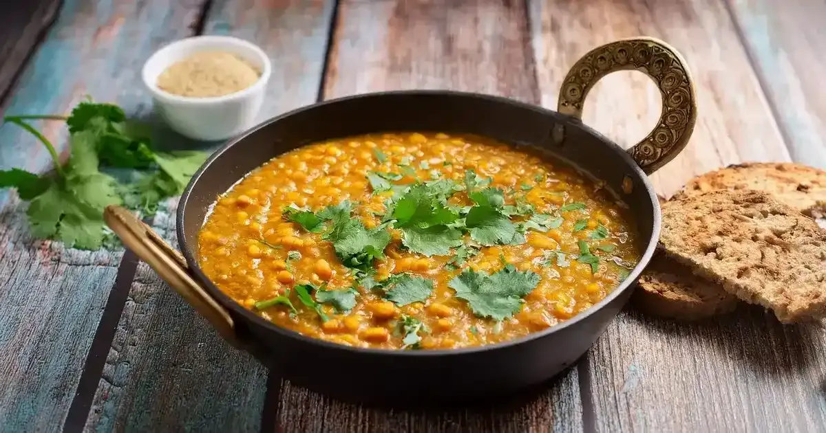 Ein Teller mit proteinreichem Linsendal und Vollkornbrot, dekoriert mit frischem Koriander.
