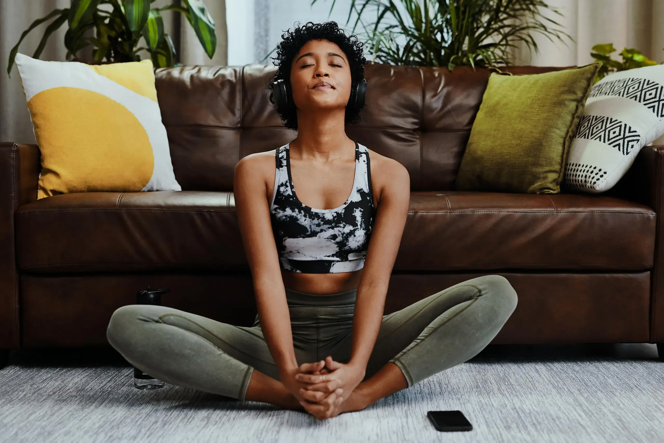 Eine junge Frau mit Kopfhörern sitzt auf dem Boden und macht Dehnübungen, um sich vom Rauchstopp abzulenken.