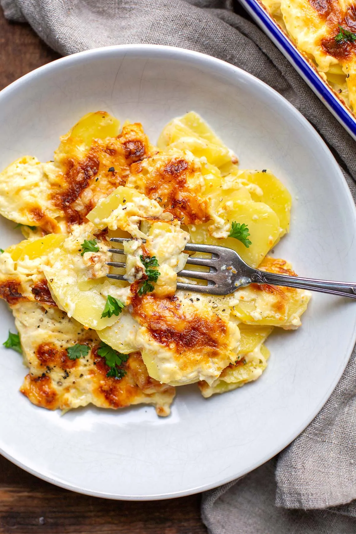 Kartoffelgratin auf einem weißen Teller mit einer Gabel