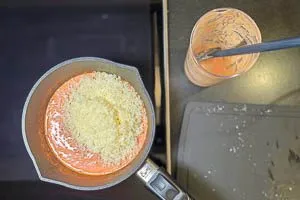 Käse und Tomatensoße zu den Zwiebeln und dem Knoblauch geben und abschmecken.