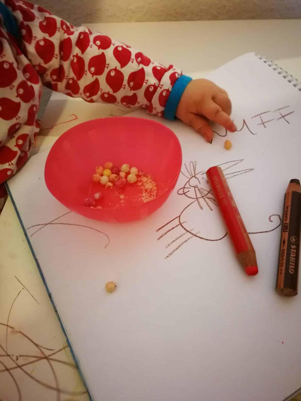 Eine Familie schaut ein Kindervideo Autos Deutsch zusammen, während Kinder mit Spielzeugautos auf dem Boden spielen.