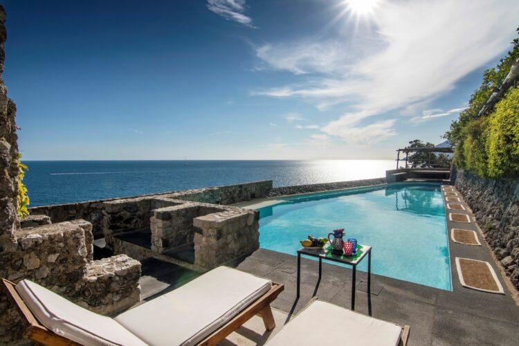 Luxuriöses rotes Cabriolet fährt entlang der Küstenstraße Mallorcas bei Sonnenuntergang