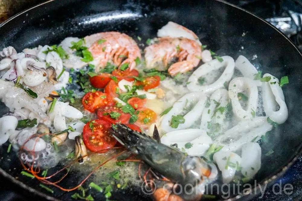 Meeresfrüchte werden zu den angebratenen Tomaten in die Pfanne gegeben.