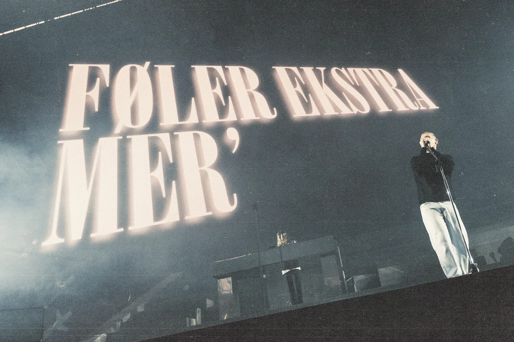 Nahaufnahme von Niels Brandt, dem Sänger von The Minds of 99, der energisch in die Menge singt, während die Lichter auf ihn gerichtet sind