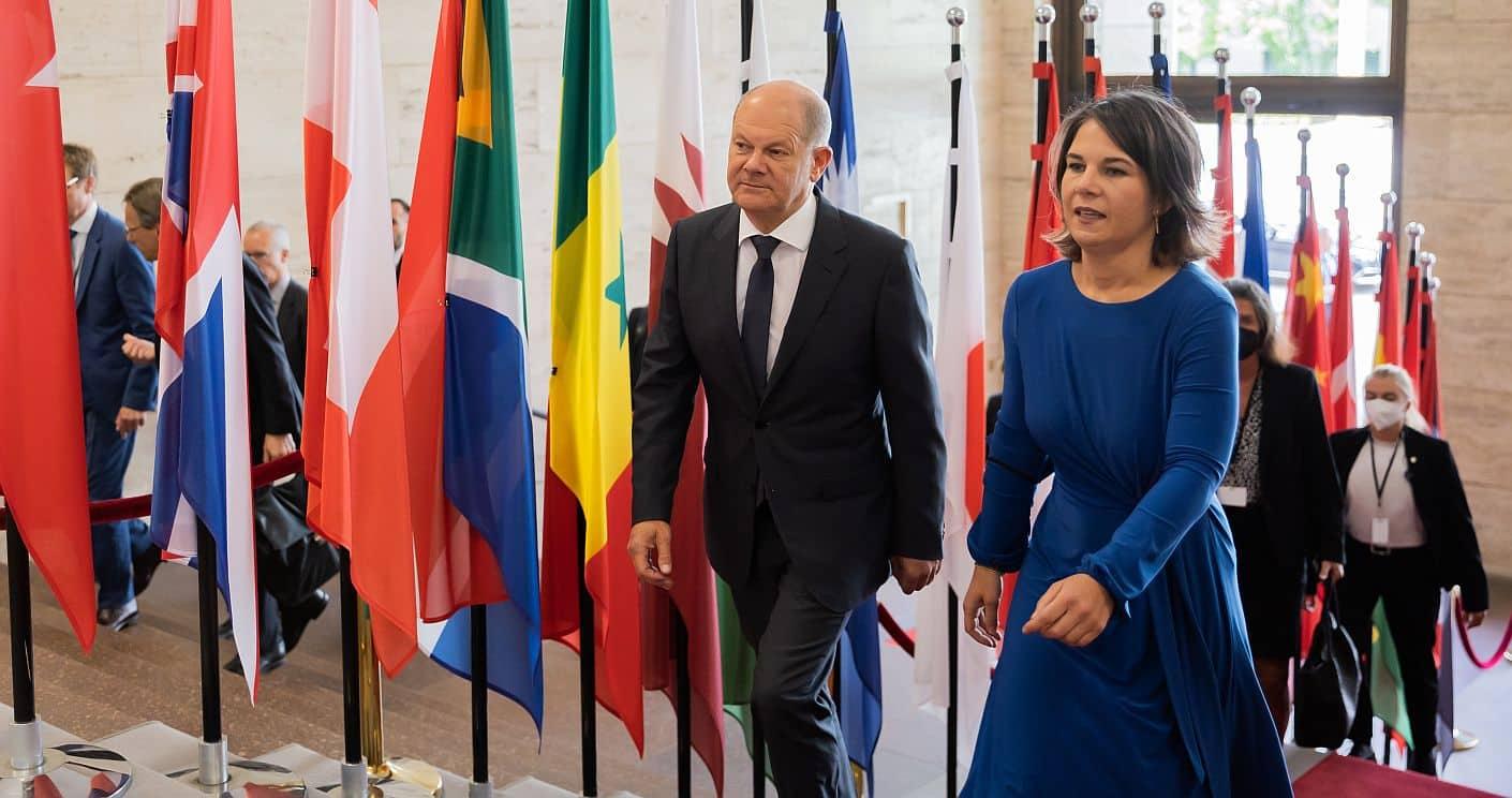 Porträt von Bundeskanzler Olaf Scholz, der nachdenklich blickt, im Hintergrund das Bundeskanzleramt