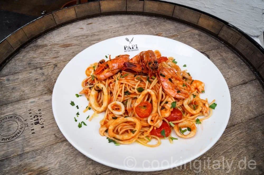 Spaghetti werden mit der Meeresfrüchte-Sauce in der Pfanne vermischt.