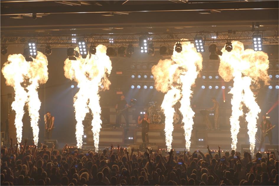 Till Lindemann in Aktion auf der Bühne, mit Rammstein-typischer Pyrotechnik im Hintergrund