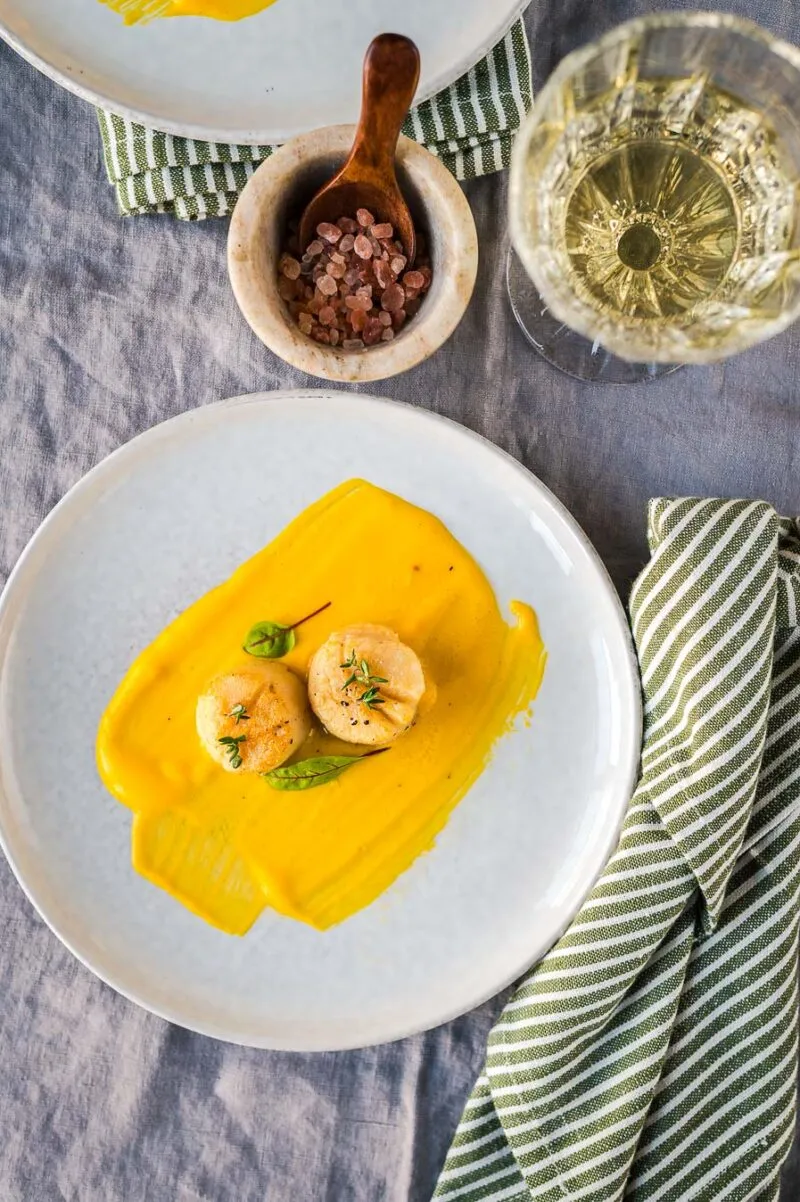 Zarte Jakobsmuscheln auf cremigem Kürbispüree.