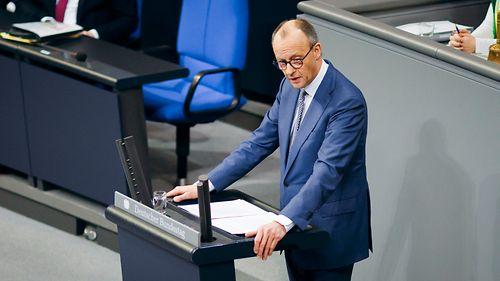 Angela Merkel bei einem Europäischen Gipfel, die Hand auf einem Dokument mit ihrer Unterschrift