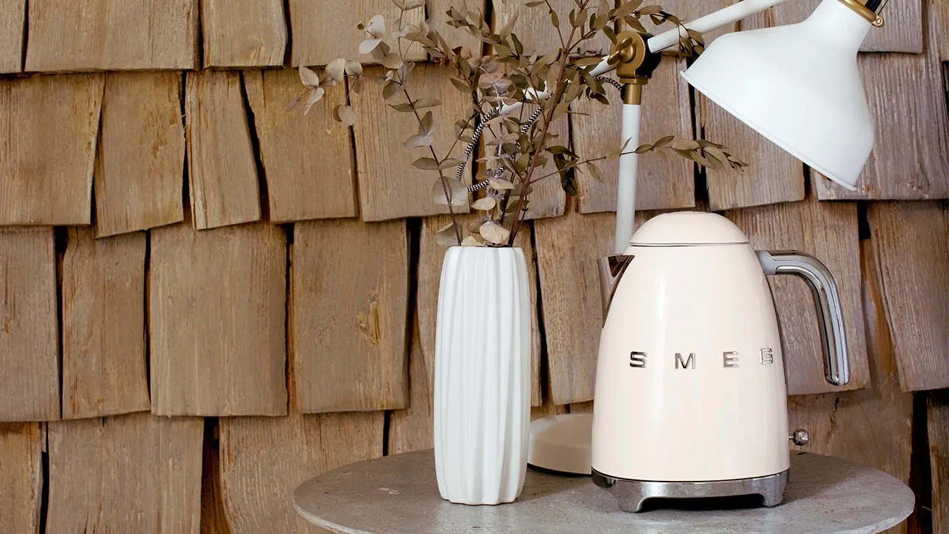 Smeg Wasserkocher in Creme auf einem Beistelltisch neben einer weißen Vase