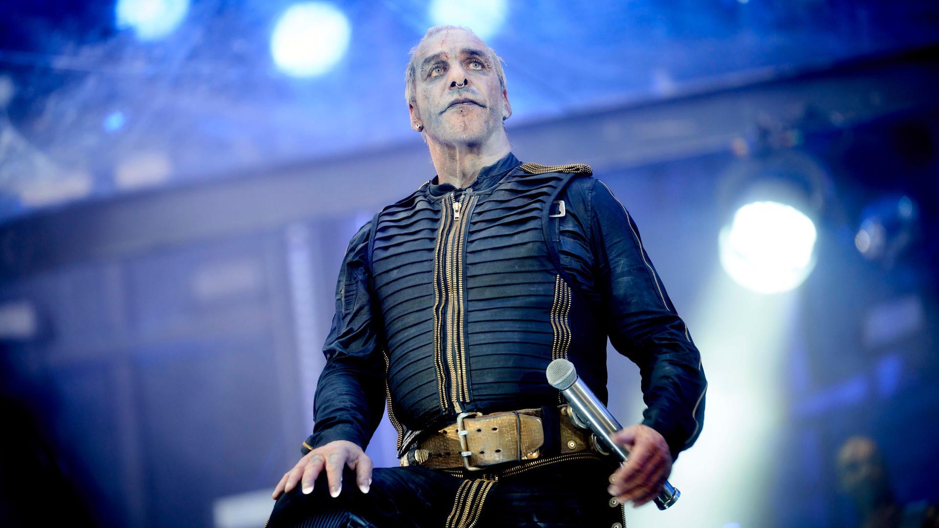 Till Lindemann in voller Aktion auf der Rammstein-Bühne, Feuer und Rauch im Hintergrund